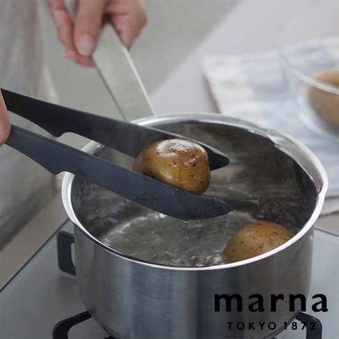 marna TOKYO 1872 品牌標誌，手持黑色食物夾將一顆馬鈴薯放入滾水中烹煮，鍋中還有另一顆馬鈴薯，爐架清晰可見。