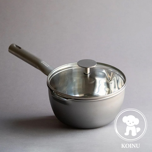 一個帶有玻璃鍋蓋的銀色三層不鏽鋼雪平鍋，鍋柄為灰色，鍋身呈現霧面質感。