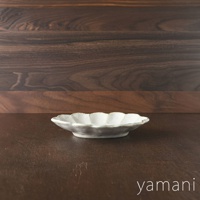 一個18公分、米白色、帶有六道花瓣紋理的橢圓形陶瓷料理盤，盤緣呈現略帶仿舊的質感，置於深棕色木質檯面上。