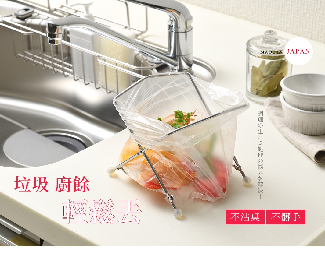 銀色金屬支架，支撐透明塑膠垃圾袋，內含廚餘，垃圾架置於廚房白色檯面上，背景為不鏽鋼水槽、水龍頭和置物架。