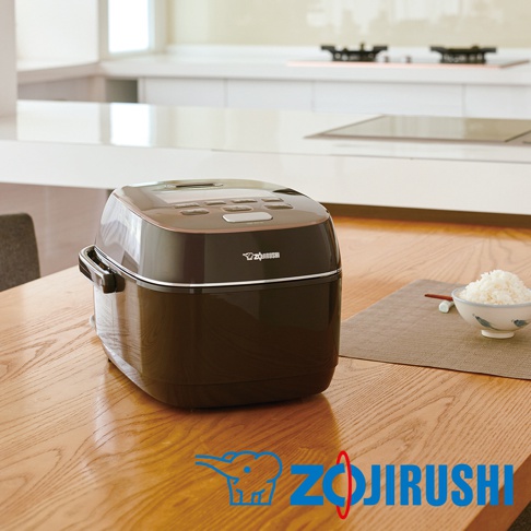 深棕色鐵器豪熱羽釜壓力IH電子鍋，設有銀色裝飾線條和多個操作按鍵，置於木質桌面。