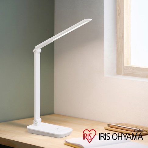 白色LED檯燈，可折疊設計，具有無線充電功能，放置於木質桌面，背景有窗戶和綠色牆面。