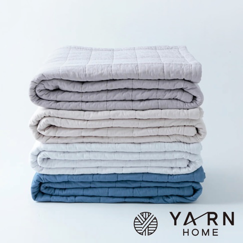 UKIHA 脫脂棉混紗速乾格紋枕套堆疊展示，顏色包含淺灰、米白、淺藍與深藍。枕套表面有細緻的格紋縫線。