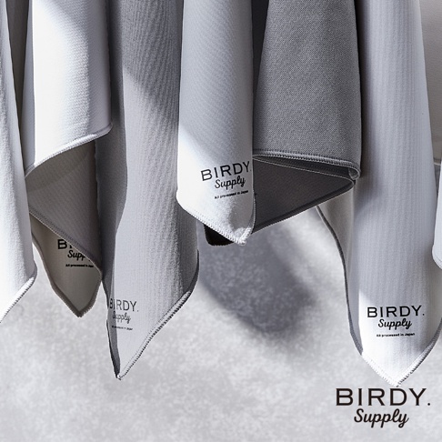 數條超細纖維萬用擦拭巾懸掛著，有白色、淺灰色和深灰色。布料表面有細小的紋理，邊緣縫有滾邊。部分擦拭巾上印有黑色「BIRDY. Supply」的品牌標誌和「All processed in Japan」字樣。