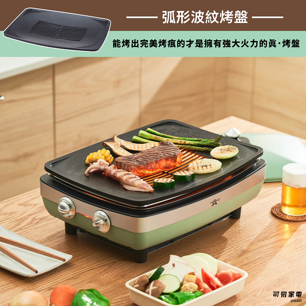 綠色烤盤上煎烤著牛排、玉米、花枝、蘆筍和櫛瓜，烤盤下方有兩個銀色旋鈕，整體呈現簡約現代的風格。