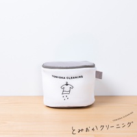 白色網狀洗衣袋，附有灰色網狀提蓋，袋身印有「TOMIOKA CLEANING」字樣及一個衣架吊著一件衣服，下方有水滴圖案。