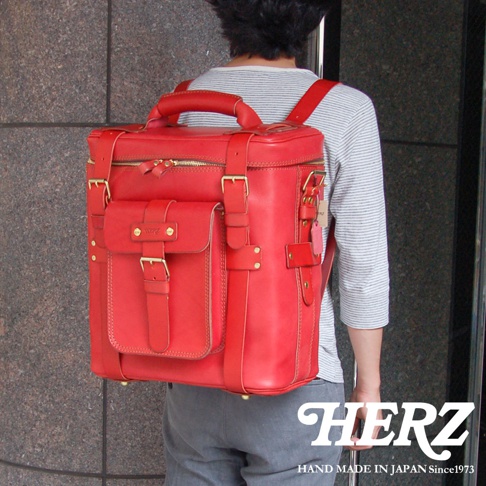 職人手作紅色皮革大型三用旅行後背包，配有黃銅扣環和拉鍊，正面有一個帶有皮帶和扣環的翻蓋口袋，側面有調節帶和掛飾，質感厚實。