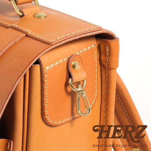 職人手作皮革小學生書包，淺棕色皮革，帶有金屬扣環和縫線細節，展現日式職人風格。