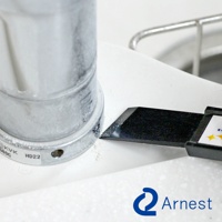 一個銀色金屬圓柱體旁，一個黑色刮刀的尖端正刮除白色表面的污垢。