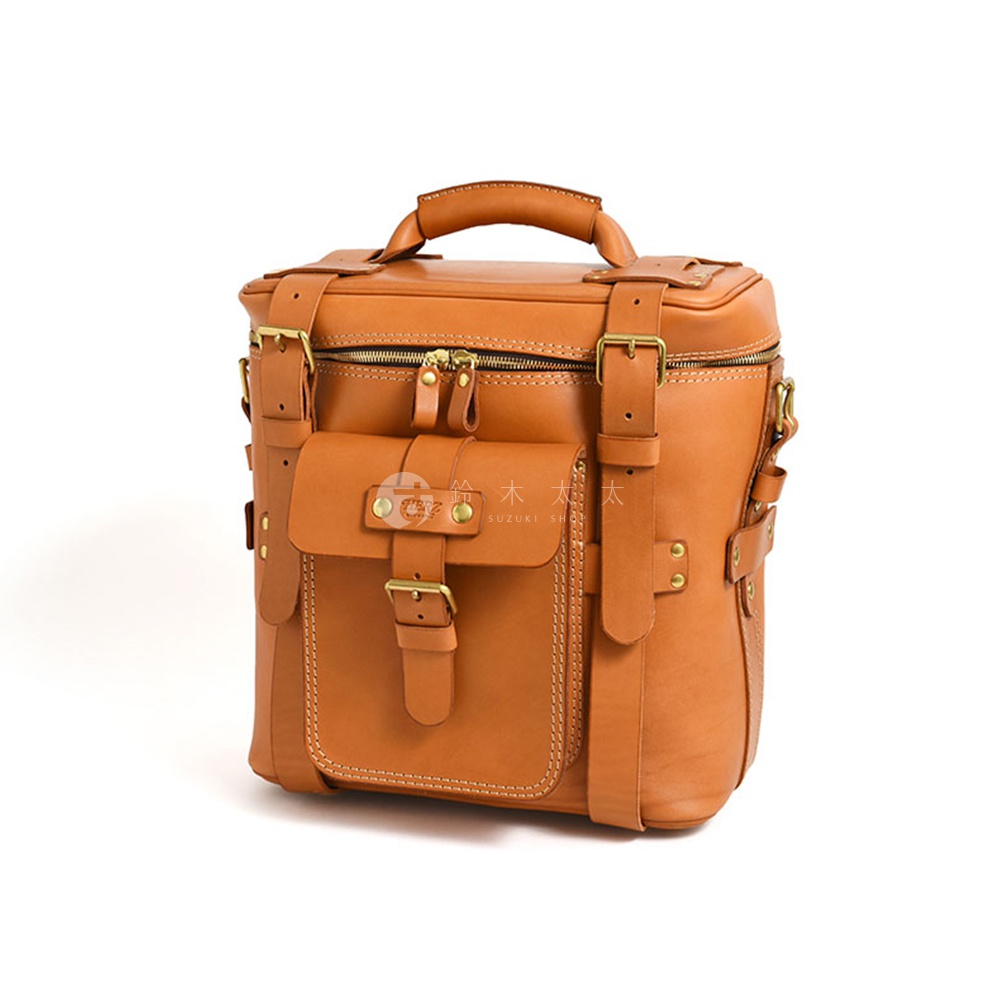 一款淺棕色職人手作皮革大型三用旅行後背包，配有金屬釦環、拉鍊及多個收納口袋，風格復古。