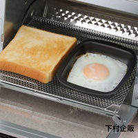 烤箱烤架上放置著一片金黃色吐司和一個黑色迷你方形烤盤，盤中煎著一個太陽蛋，蛋黃呈橘黃色，蛋白已凝固。