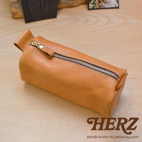 一個棕褐色、職人手作的皮革多用途收納筆袋，配有金色拉鍊和皮革拉頭。