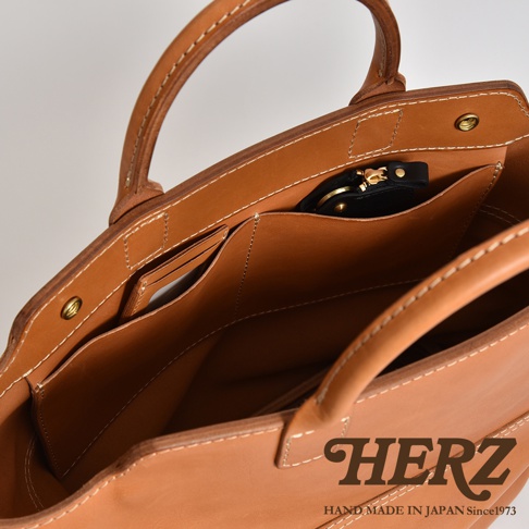 職人手作皮革大容量兩用托特包 T-8，呈現原色皮革質感，內部有卡片夾層與拉鍊小包，縫線清晰，設計簡約實用。