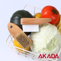 一個裝滿各種新鮮蔬菜水果（包括南瓜、番茄、白菜、玉米、檸檬和一顆馬鈴薯）的白色金屬網籃，籃子裡有兩支木柄的蔬果刷，其中一支是天然豬毛刷，另一支是纖維毛刷。