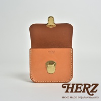 淺棕色皮革製作的方形腰包，翻蓋開啟，配有金色金屬鎖扣。包身有縫線細節，正面壓印有「HERZ」品牌標誌。