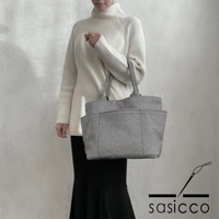 一名女性手提著一個灰色刺子織紋路的托特包，包包有外部口袋，整體為簡潔的設計。