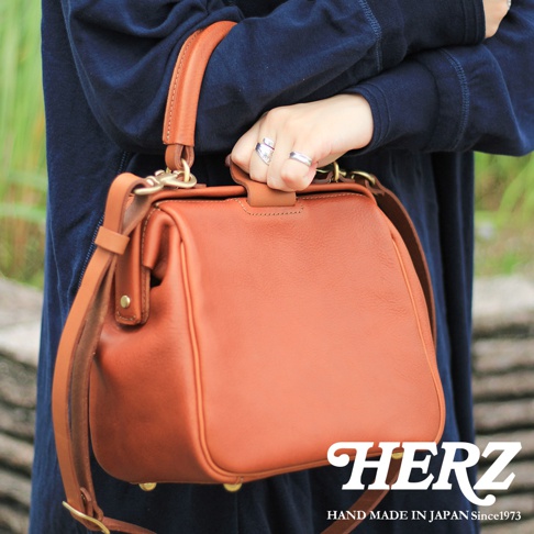 職人手作皮革Organ兩用方形口金托特包，展示為棕褐色，採用質感皮革製成，配有兩個提把和一個可拆卸斜背帶，並有金色金屬配件點綴。