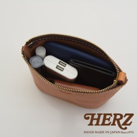 職人手作皮革三角收納包，棕色皮革材質，包內裝有手機、行動電源、口紅與卡夾。