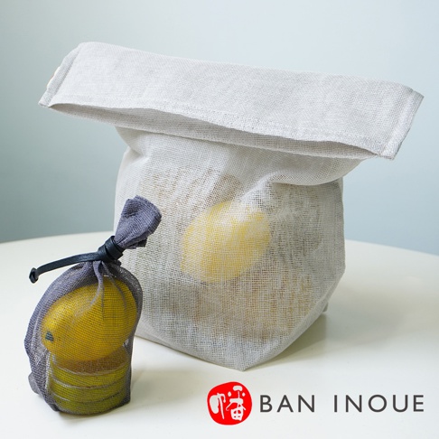 淺灰色蚊帳布製成的開口收納袋，內裝黃色蔬果，前方有一個同材質、附黑色繫繩的灰色小網袋，內裝少量黃色蔬果。