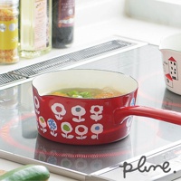 紅色琺瑯單柄牛奶鍋，鍋身印有白色花朵圖案，鍋內裝有湯品，放置於電磁爐上。