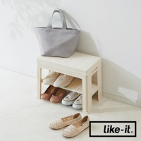 米白色塑膠材質的玄關穿鞋收納椅，上方擺放一個灰色帆布托特包，收納椅下方兩層展示有四雙鞋子，包括兩雙帆布鞋和兩雙高跟鞋。