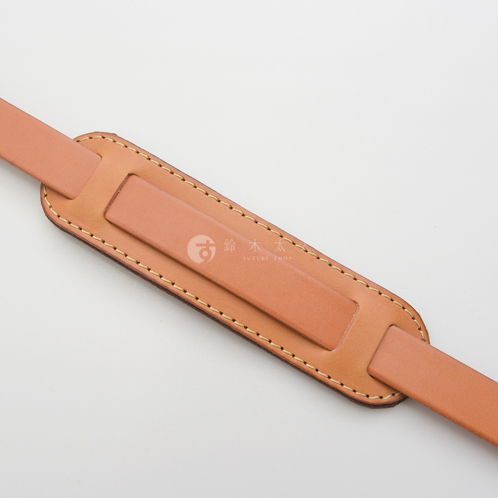 職人手作皮革肩墊，淺棕色，由兩層皮革拼接而成，邊緣以米色縫線車縫，中央有品牌標誌。