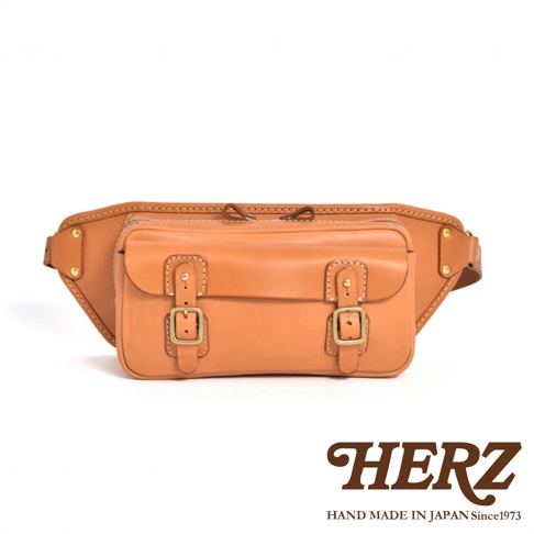 職人手作皮革騎士隨身斜背包 F-12，採用鞣製皮革製成，呈現自然的淺棕色。包款設計有雙扣環裝飾的前袋，整體線條簡潔，適合隨身攜帶。