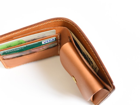 職人手作皮革經典掀蓋扣式雙折短夾 (WS-5)，展示焦糖色皮革材質，內含多張信用卡及日圓鈔票，錢包縫線清晰，部分細節特寫。