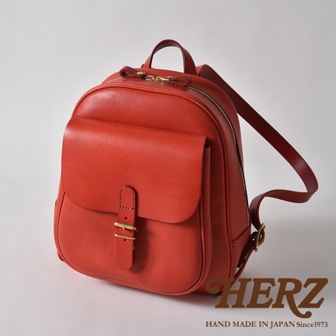 紅色皮革迷你後背包，帶有立體前袋，皮革帶扣和金色拉鍊。