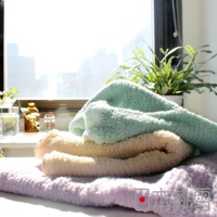 疊放的今治細絨毛巾，由上至下分別為淺綠色、米黃色和淺紫色，觸感柔軟，毛圈蓬鬆，在窗邊陽光照射下顯得溫暖。