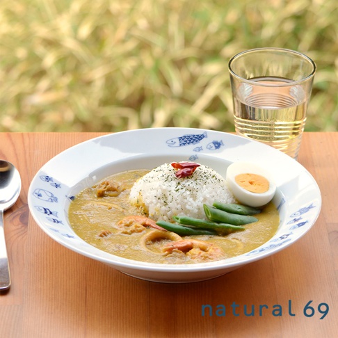 白色陶瓷義大利麵盤，內盛放著米飯、咖哩醬、蝦仁、青豆和水煮蛋，盤緣飾有藍色魚形圖案。