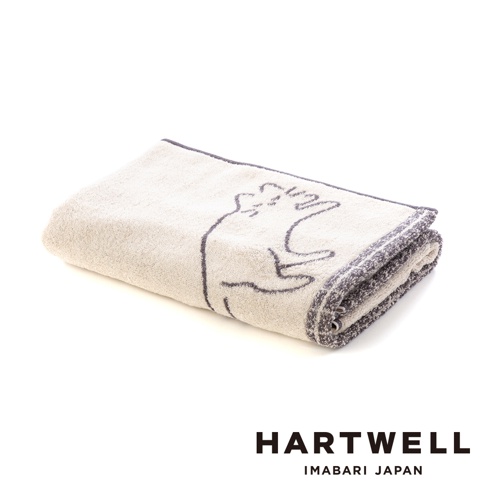 一條摺疊整齊的米色系Hartwell品牌今治浴巾，表面有簡約的線條勾勒出一隻午睡貓咪的圖案，邊緣飾有深灰色滾邊，整體呈現日式簡約風格，白色背景襯托出產品細節。