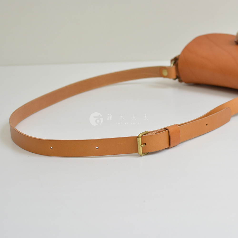 職人手作皮革鹿角扣繩肩背包，淺棕色真皮材質，配有可調節長度的皮質背帶，裝飾有黃銅色金屬扣環。