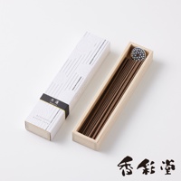 一盒印有白色線條與圓形圖案的紙盒，內裝有約八種不同香氛線香，線香呈深棕色，置於木質淺盒中，盒蓋上附有黑色飾帶，印有「木蓮」與「Magnolia」字樣。