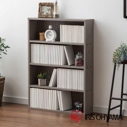 灰木紋四層收納書櫃，擺放著白色漫畫書、裝飾品、小盆栽及復古相機。