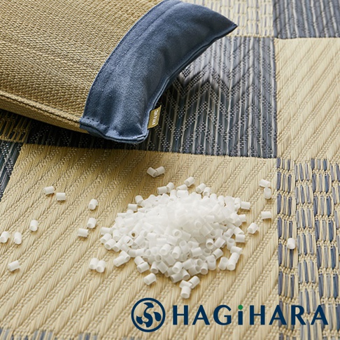 藺草編織的枕頭，局部搭配藍色布料，旁邊散落著白色填充物，背景為藺草編織的格紋圖案。