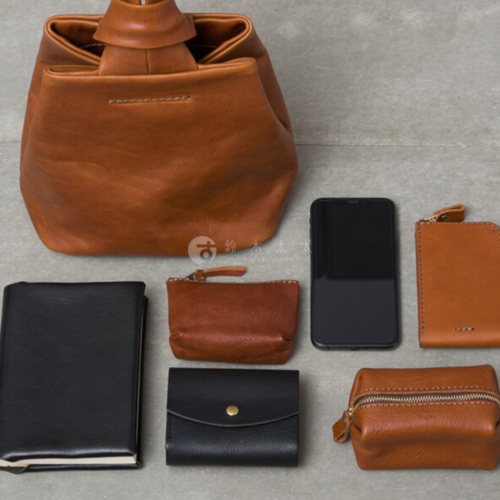 職人手作皮革Organ單柄手提包，搭配黑色筆記本、棕色零錢包、黑色皮夾、手機及棕色化妝包，展現多樣化的收納組合。