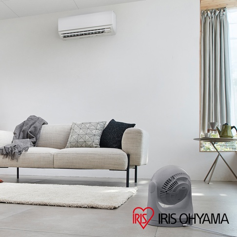 灰色的PCF-MKM15 空氣循環扇，帶有圓潤的機身和可調節的風向角度，放置在客廳地板上。