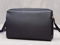 黑色皮革極簡風拉鍊單肩包，附有金色拉鍊和肩帶扣環，側面有精緻縫線。