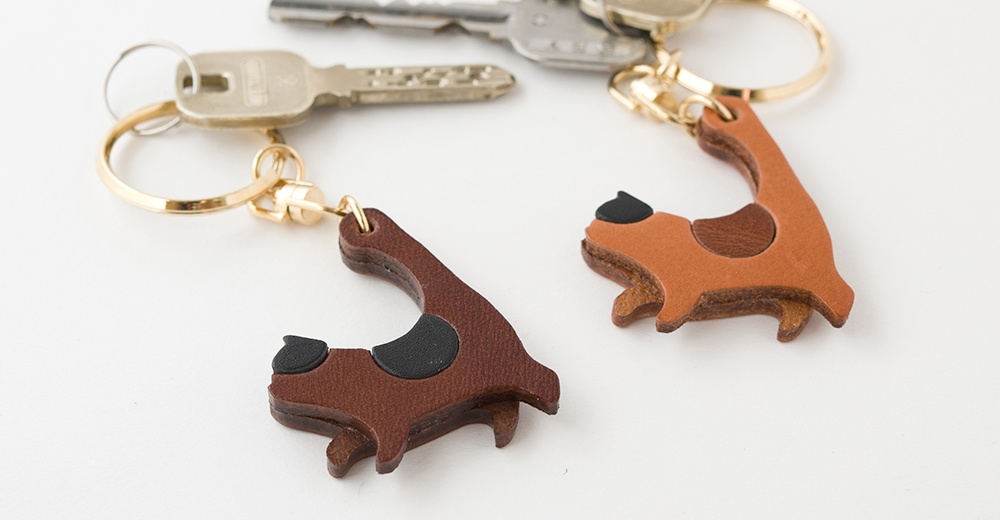 職人手作皮革貓咪造型鑰匙圈，由棕色和深棕色皮革製成，貓咪造型可愛，搭配金色鑰匙圈，簡約實用。