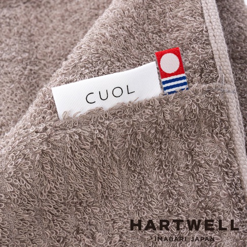 柔軟的淺棕色毛巾，織有品牌標誌 CUOL 和 HARTWELL，以及今治日本的字樣。