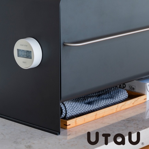 UtaU 品牌抽屜式收納櫃，側面有圓形數位計時器，下方抽屜內放置著折疊的紋理毛巾。