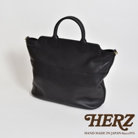 黑色皮革手作托特包，具有簡潔的設計和兩條提把。包身前方有兩條橫向縫線裝飾，整體呈現自然垂墜感。