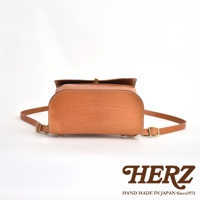 職人手作皮革翻蓋迷你後背包，採用天然皮革材質，呈現溫潤的淺棕色調。包身線條圓潤，搭配簡約的翻蓋設計與金屬扣環，展現經典質感。