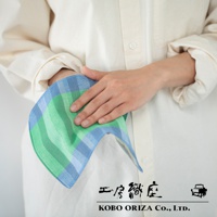 一條長方形手帕，採用藍色和綠色格紋圖案，材質為棉。手帕由人手持握，展示其柔軟的質地和精緻的編織。