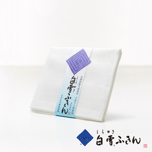 一疊白色棉質布料，以藍色圖案紙帶捆綁，紙帶上印有日文文字及紫色菱形圖案，布料質感細緻。