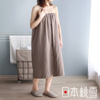 一位女性穿著一件淺棕色的棉紗混紡平口鬆緊浴巾裙，裙子上有灰色的鈕扣。