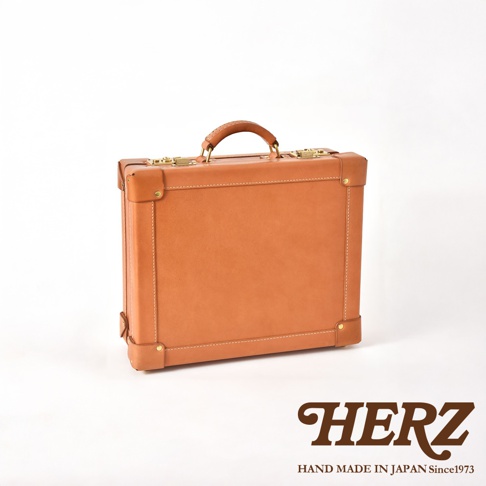 職人手作皮革英倫風便攜手提行李箱，以棕褐色皮革製成，配有金色金屬扣環和頂部提把。箱體邊緣有縫線裝飾，底部和四角有加固皮革。