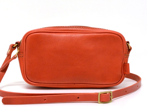 亮橘色皮革製成的隨身單肩小包，方形設計，頂部有拉鍊開口，附有可調節長度的細肩帶及金色金屬調整環。