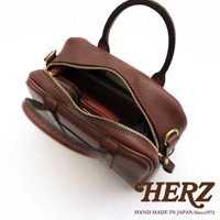 HERZ 職人手作皮革兩用迷你波士頓包，深棕色牛皮革材質，圓潤包身設計，拉鍊開口，內有小皮夾，手提握把，下方有品牌標誌，標示 HAND MADE IN JAPAN Since1973
